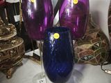 purple and blue wine glasses sitting on top of a white table