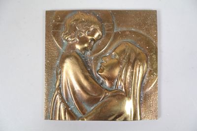 une photo représentant une plaque métallique sur laquelle figure l'image d'une femme tenant un enfant dans ses bras