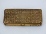 a gold plated cigarette case with a checkered pattern