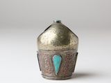 an old silver and turquoise vase sitting on top of a white surface