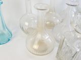 Plusieurs vases en verre sont alignés sur une surface blanche