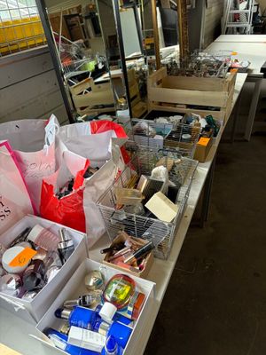 Des boîtes contenant des articles variés sont alignées sur une table dans un atelier.