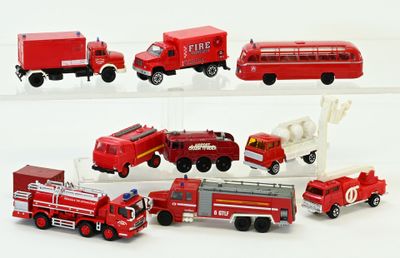 Plusieurs camions de pompiers et camions miniatures sont alignés sur une surface blanche