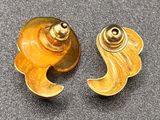 pair of gold tone earrings with wavy design on a black surface