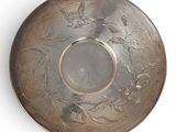 a silver plate with a design on it on a white surface