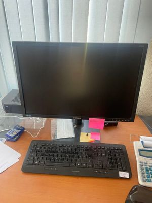 un écran d'ordinateur et un clavier posés sur un bureau, avec une calculatrice et une autre calculatrice
