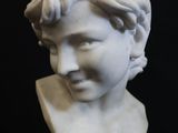 a white marble bust of a young girl with a flowered head