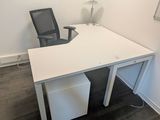 un bureau blanc avec une chaise noire dans un coin
