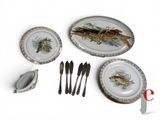 a plate with a fish on it next to a spoon and fork
