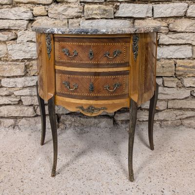 an old wooden chest of drawers with a marble top in front of a stone wall