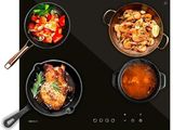 four pans of food cooking on a black stove top