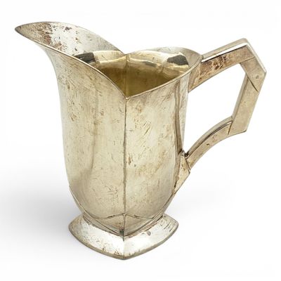 a silver pitcher that is sitting on a white surface