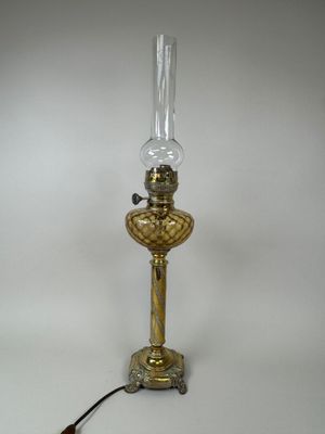 an antique brass table lamp with a glass shade on top of it