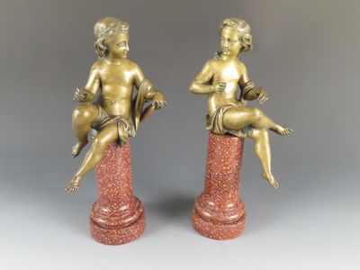 paire de figurines anciennes en bronze représentant un garçon et une fille assis sur un socle