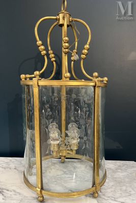 a brass and glass lantern with two candles inside on a marble table