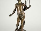 an antique bronze statue of a man holding a harp
