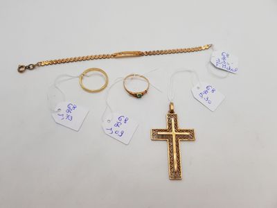 Plusieurs bagues, une croix et un bracelet sont posés sur une table