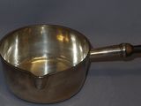 a small metal pot with a wooden handle on a table