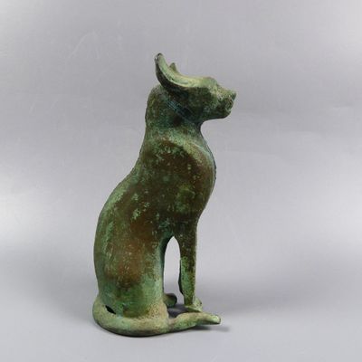 an ancient bronze statue of a cat sitting on its hind legs