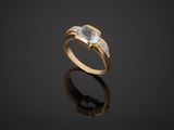 a gold ring with a blue topaz stone and diamonds on a black surface