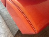 a close up of a red leather couch on a wooden floor