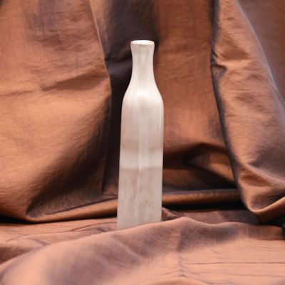 a small white bottle sitting on a brown cloth