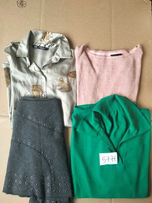 three pairs of tops and pants sitting on top of a cardboard box