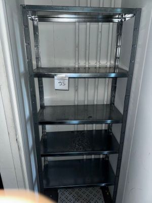 une étagère métallique avec des tablettes en verre, placée dans un coin de la pièce