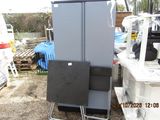 a refrigerator that is next to a chair in a yard