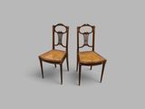 une paire de chaises anciennes avec des dossiers en rotin sur fond gris
