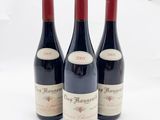 trois bouteilles de vin rouge sont alignées sur une surface blanche
