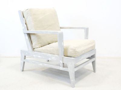 une chaise blanche avec un coussin posé dessus, dans une pièce