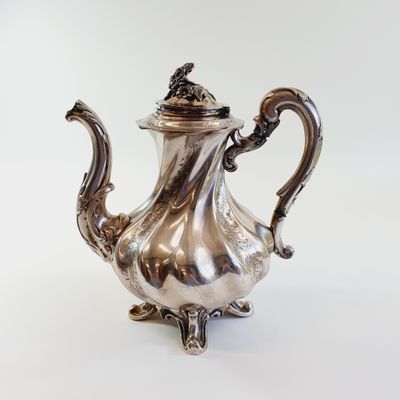 silver plated tea pot with a bird on the top