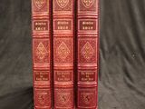 trois livres en cuir rouge posés sur une table recouverte d'un tissu noir