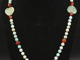 un collier de perles orné d'un pendentif en pierre verte, rouge et blanche