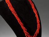 a close up of a necklace on a mannequin with a red bead