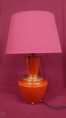 une lampe de table orange surmontée d'un abat-jour rose