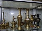 many brass vases on display in a glass case