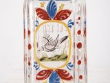 a glass bottle with a bird on it on a table