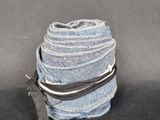 trois pantalons en jean empilés les uns sur les autres sur une surface noire