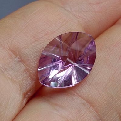 Quelqu'un tient dans sa main une très jolie pierre de couleur violette.
