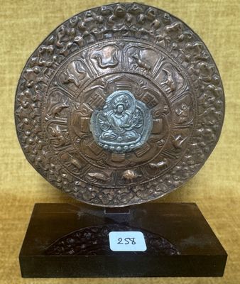 une plaque en bronze ornée d'un motif, posée sur un socle noir