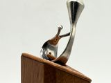 a metal object on a wooden stand with a white background