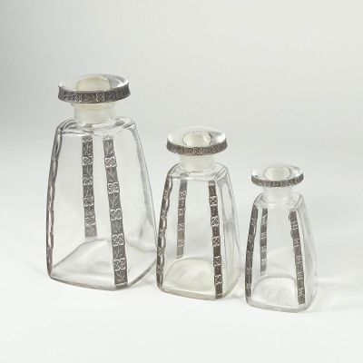 three clear glass bottles with silver trims and a silver lid