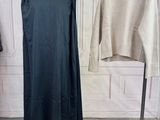 two sweaters hanging on a clothes rack in a room