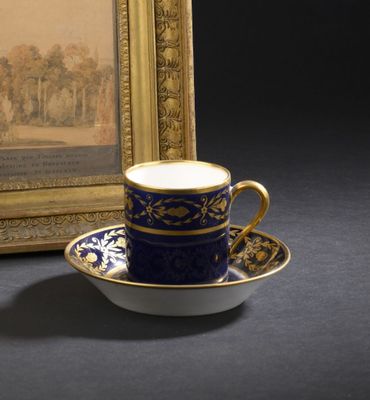 une tasse et une soucoupe posées sur une table, à côté d'un tableau