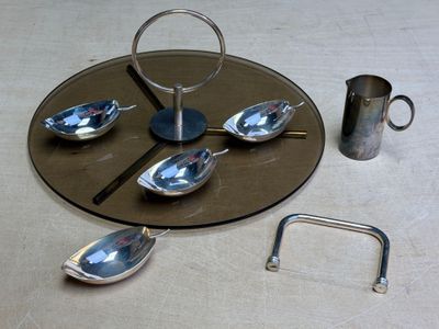 a silver plate with spoons and a silver pitcher on it