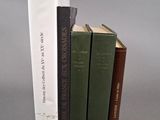 trois livres sont empilés sur une surface grise