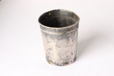 a silver cup that is sitting on a white surface