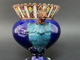 a blue vase with a gold crown on top of it